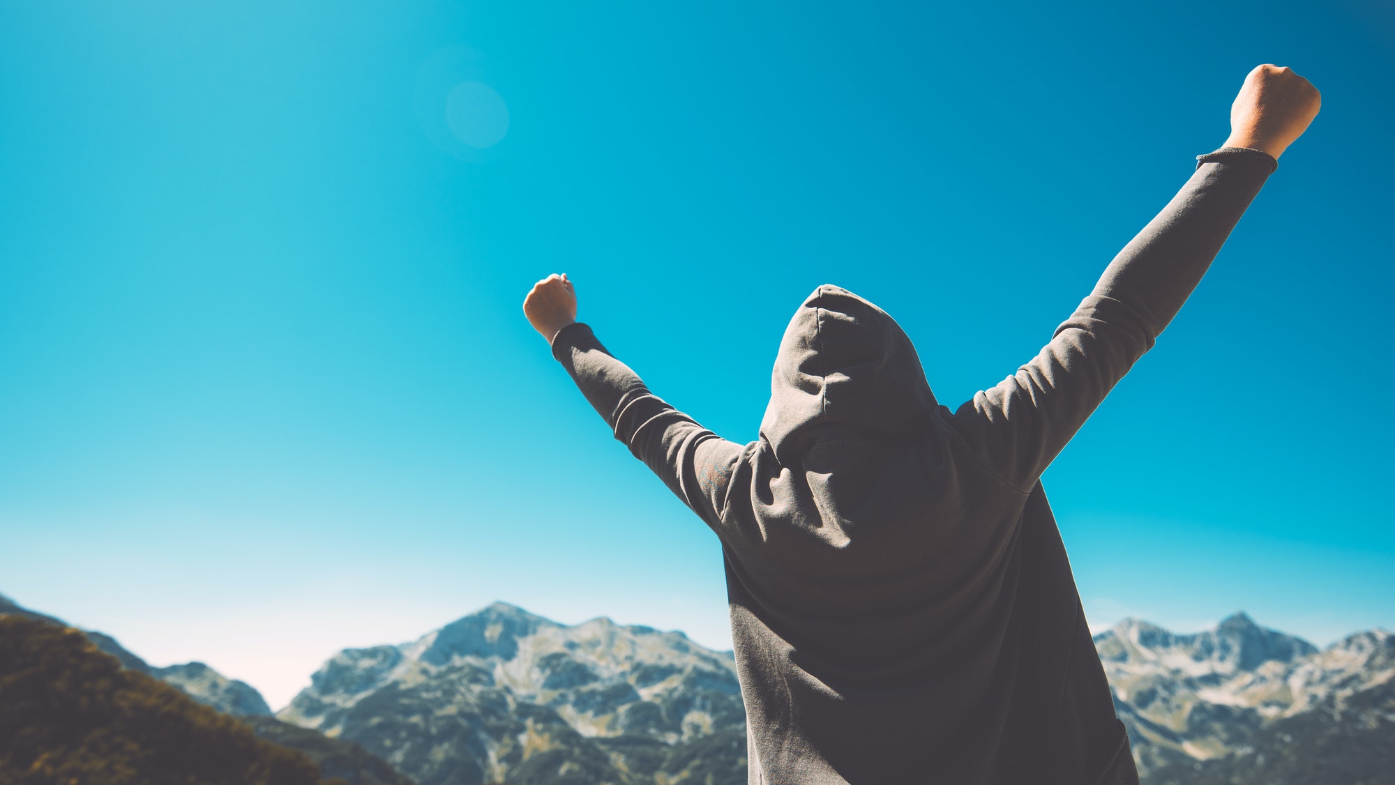 Winning and success. Victorious female person on mountain top.